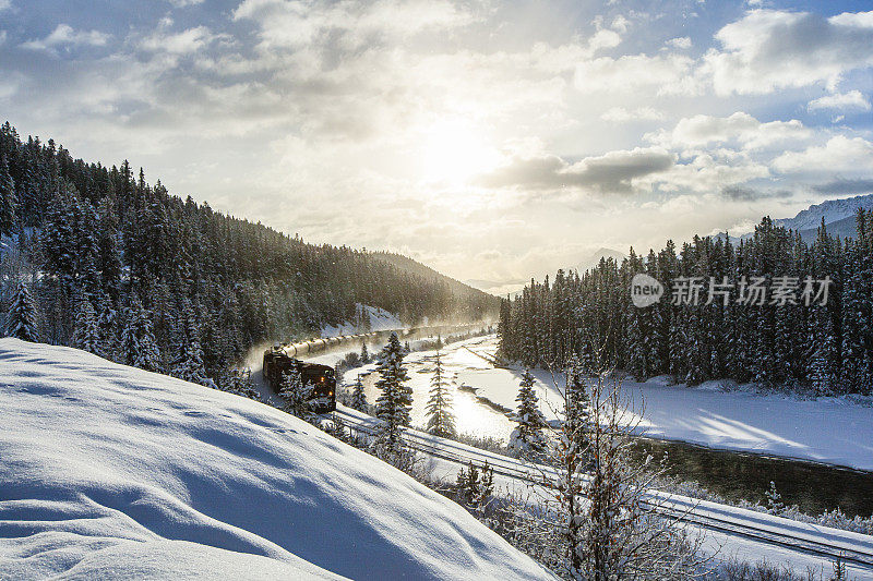 蒸汽火车穿过积雪覆盖的松树山和壮观的天空