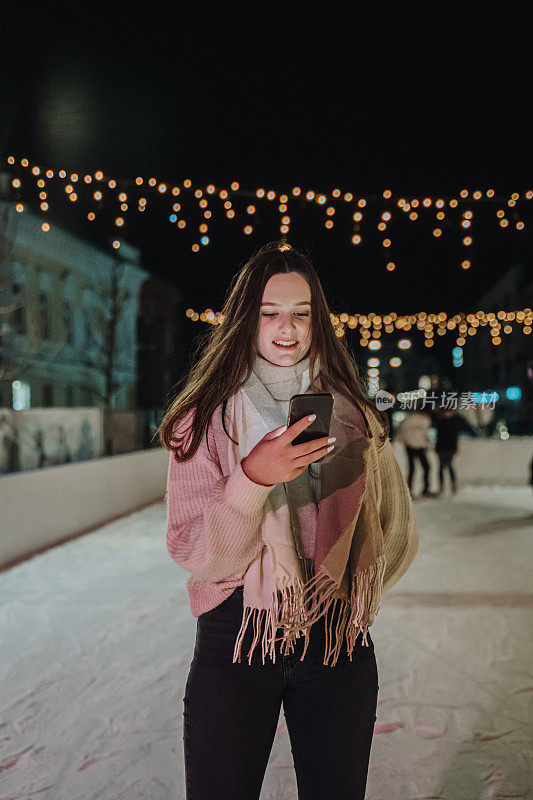 晚上站在溜冰场上玩手机的年轻女子