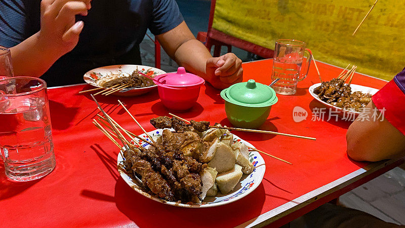 年轻的印尼男子吃沙爹鸡