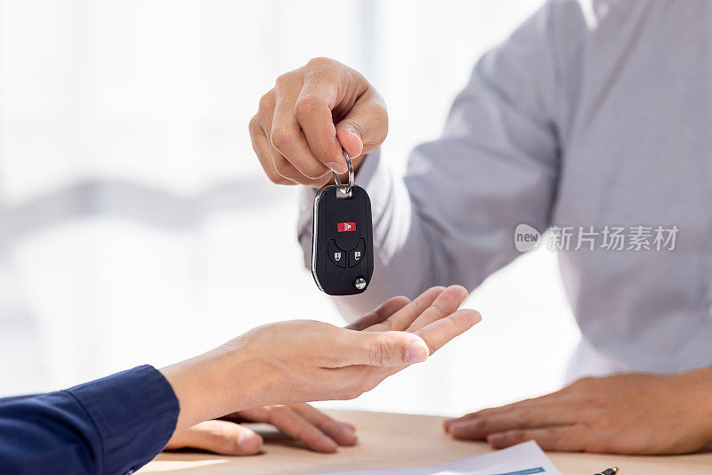 汽车保险文件或租赁概念，汽车经纪人协助他的客户，并解释汽车联系的细节。汽车钥匙买卖签约。