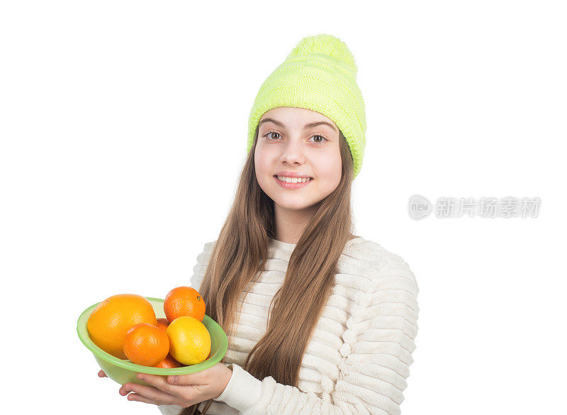 戴着帽子和毛衣的孩子拿着柑橘类水果。秋季时尚风格。暖和的衣服。
