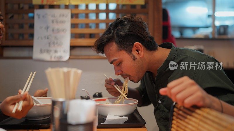 一名男游客在旅行途中在拉面店享用拉面