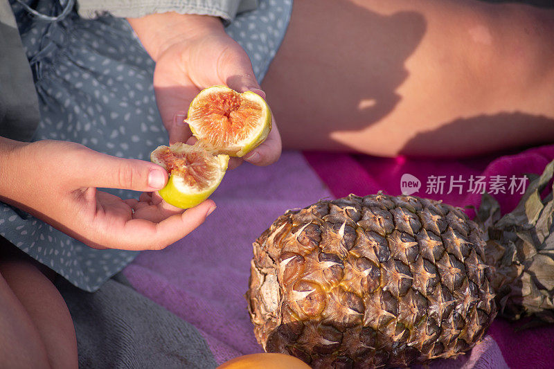 年轻女子在海滩上吃无花果