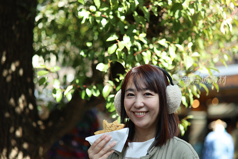 美丽的女士在街上吃甜食