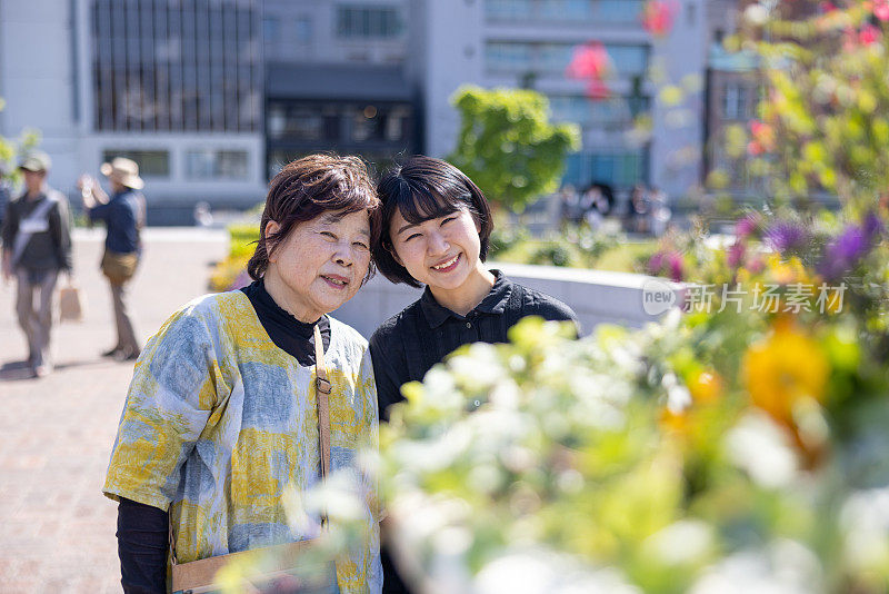 年轻女子和她的祖母站在城市公园里的肖像