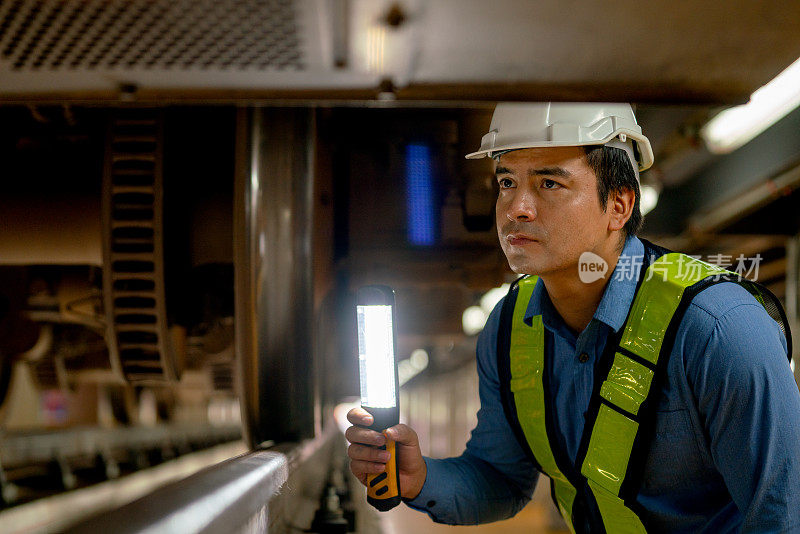 专业的工程师工人在列车工厂的工作场所用灯管进行检查和维护。