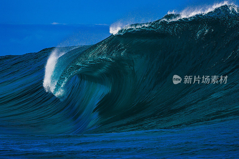 巨大的蓝色弯曲波浪在开阔的海洋上冲破一个浅海礁