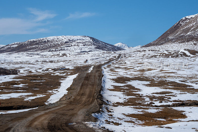 山路越野到一个高山村。积雪覆盖的狭窄山路在雪山的斜坡上。危险的越野驾驶沿着山脉的边缘和陡峭的悬崖。