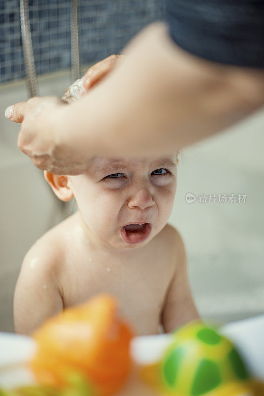 妈妈在浴缸里给婴儿洗澡，婴儿在哭