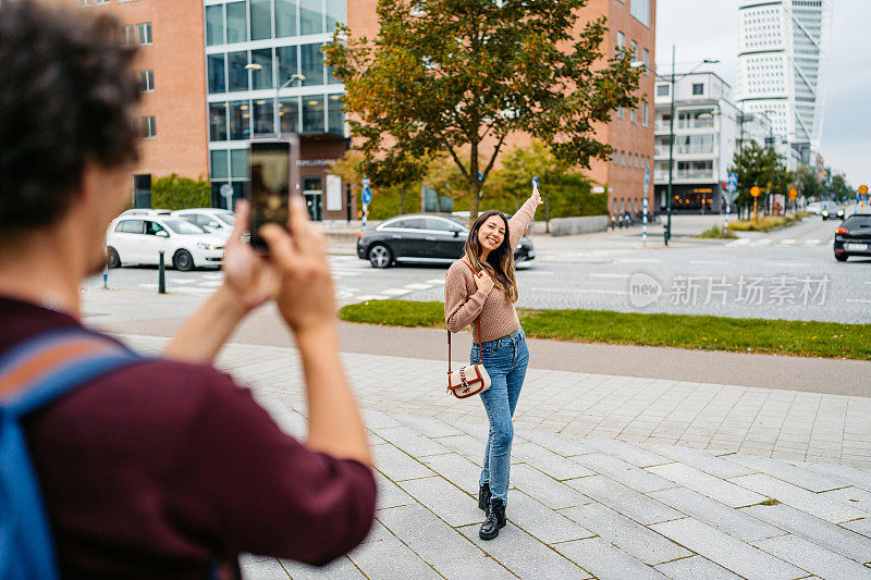 在瑞典马尔默的大街上，一个年轻人正在给他的女朋友拍照
