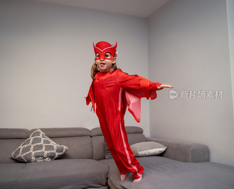 可爱的小女孩穿着红色的超级英雄装在公寓里跑来跑去，只是玩得开心，拯救了一天
