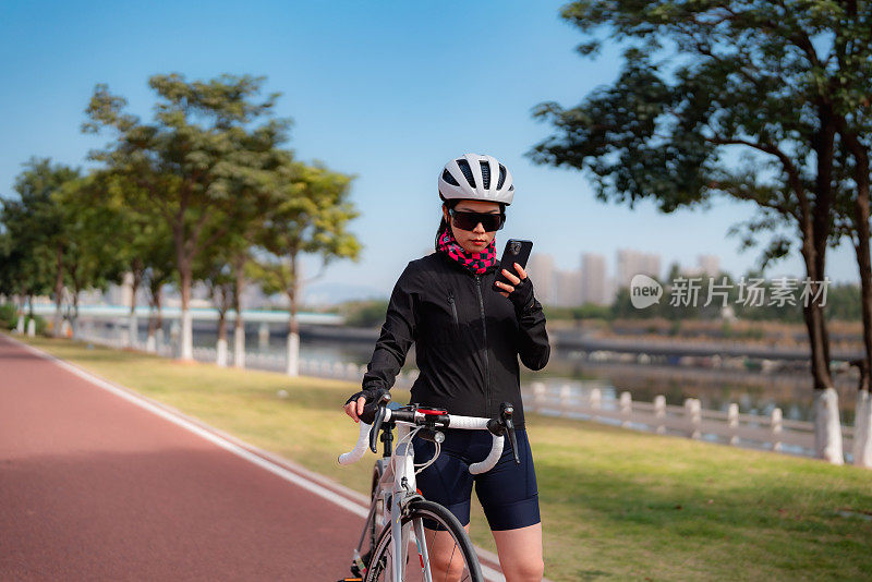 女公路自行车骑手使用智能手机