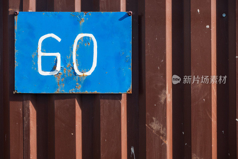 一个棕色金属栅栏的碎片，是用铁制成的。有一个古老的蓝色标志，上面写着数字60。背景。纹理。