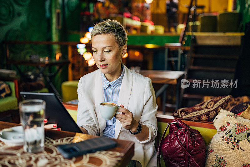 女商人在咖啡店里一边喝咖啡一边使用数码平板电脑