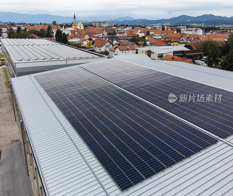 仓库屋顶上的太阳能电池板，背景是城市景观和山脉。