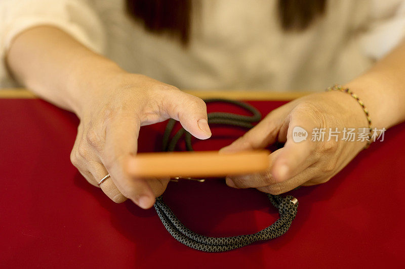 一位亚洲年轻女性用手指在智能手机上发短信。