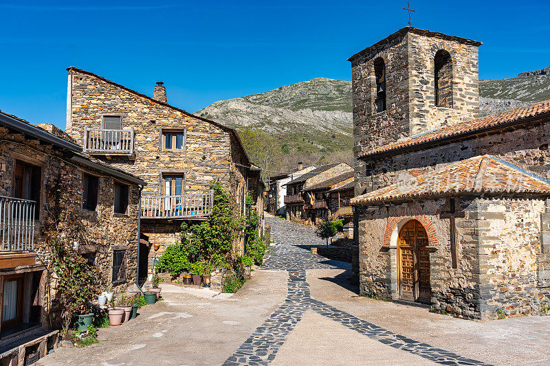 西班牙，卡斯蒂亚-拉曼查，山边的乡村教堂周围有石头房子。