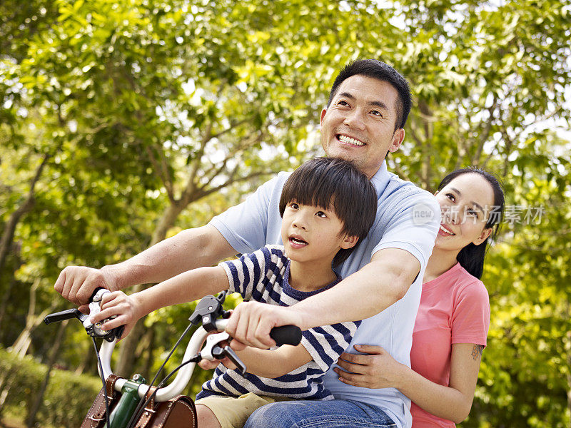 亚洲家庭在公园里骑自行车