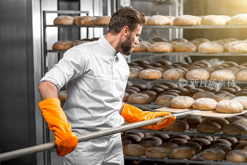 面包师正用铲子把面包放在制造车间