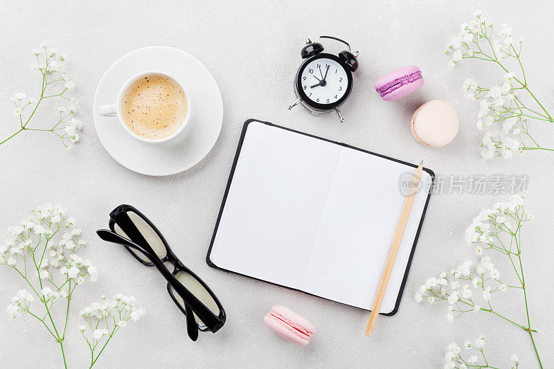 咖啡，杏仁饼干，笔记本，眼镜，闹钟和花。生活方式的概念。