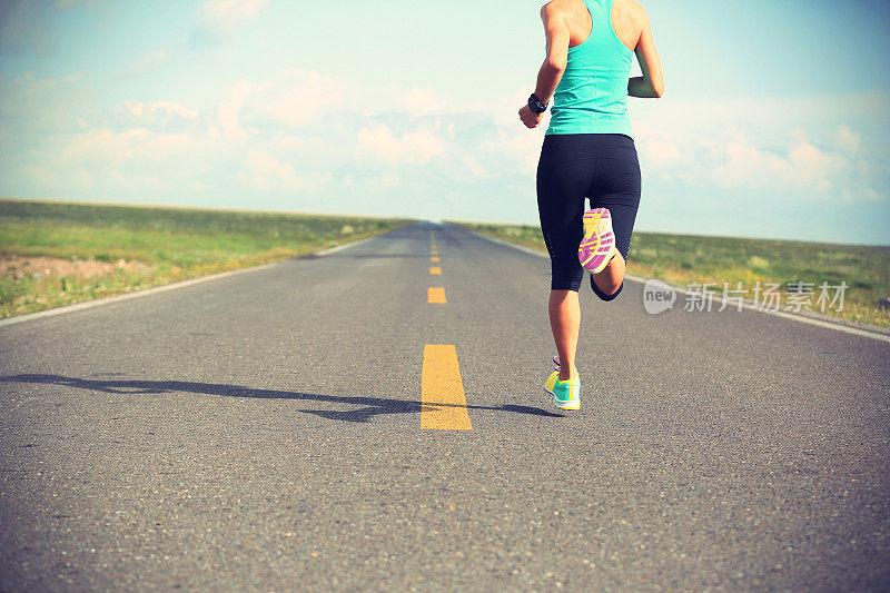 年轻的健身女运动员在公路上跑步