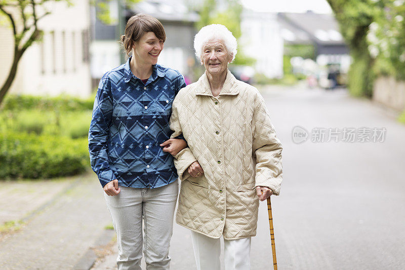 年轻的看护者帮助在街上行走的老年妇女