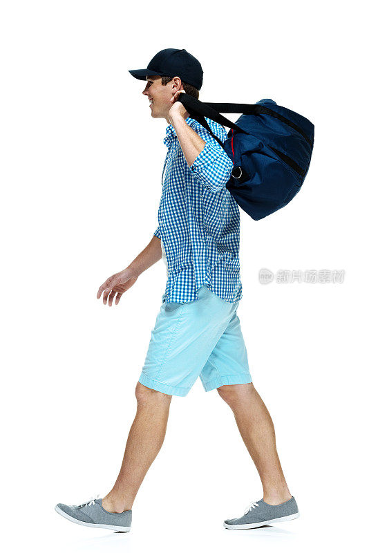 侧面的快乐的年轻人走与行李袋