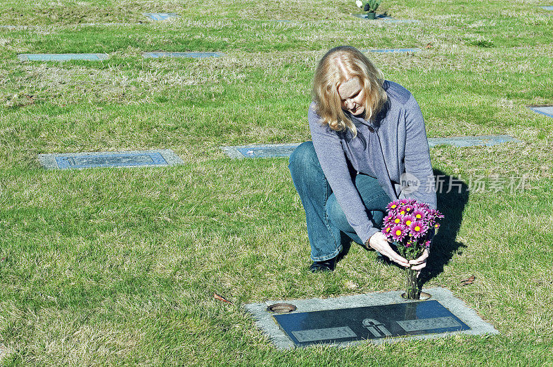 妇女在墓地的墓前献花