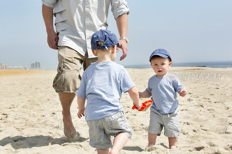 父亲和他的两个小儿子在海滩上