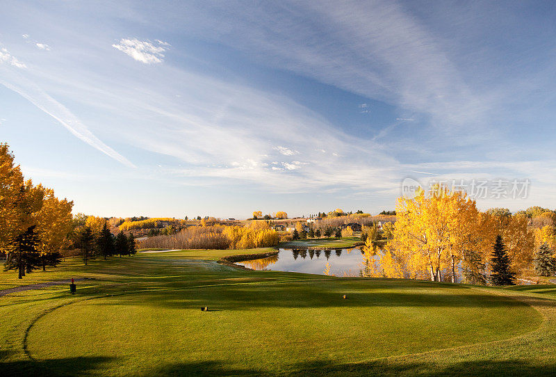 高尔夫球场景观与池塘和林区。