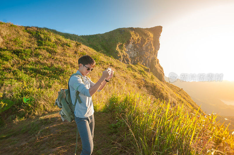 年轻的旅行者站在山上望着夕阳。