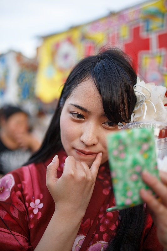 日本浴方妇女检查她的嘴唇与手镜