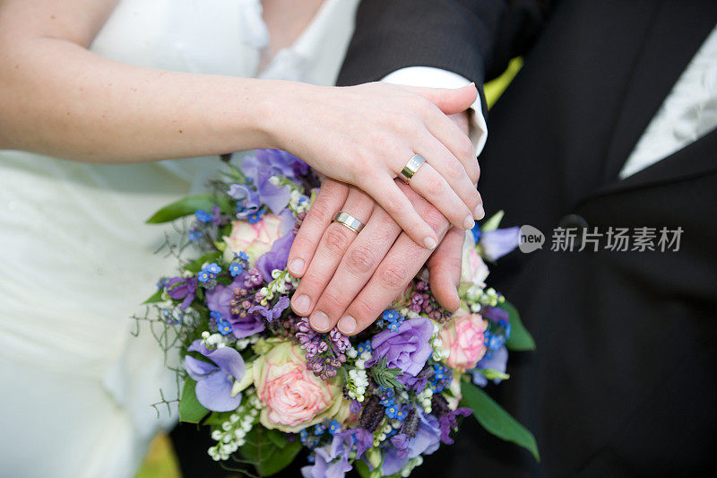 新娘和新郎的手在新娘花束上