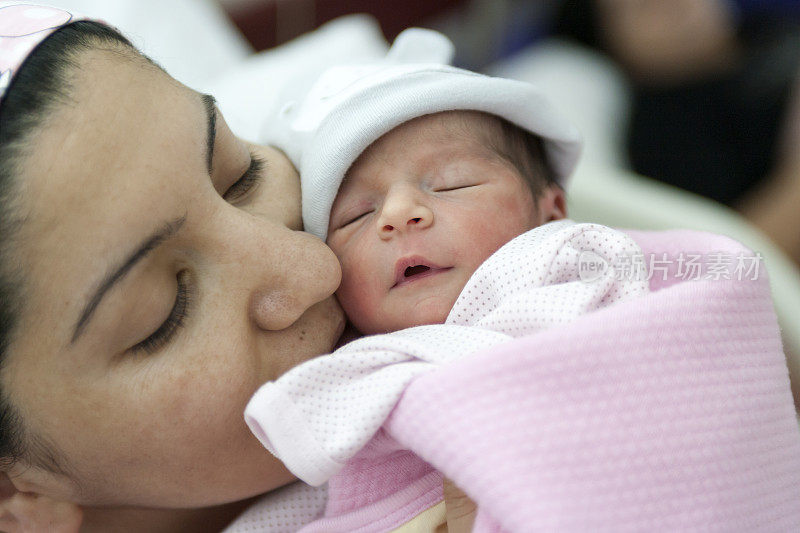 刚出生的婴儿和她的母亲一起被裹在粉红色的毯子里