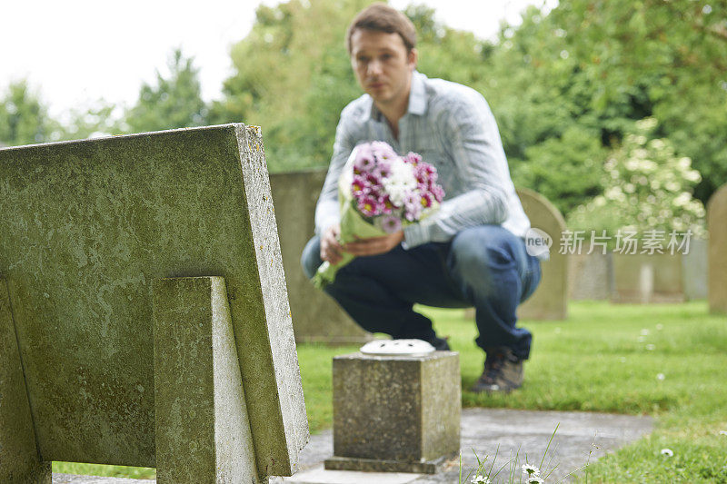 一名男子在墓地墓碑前献花