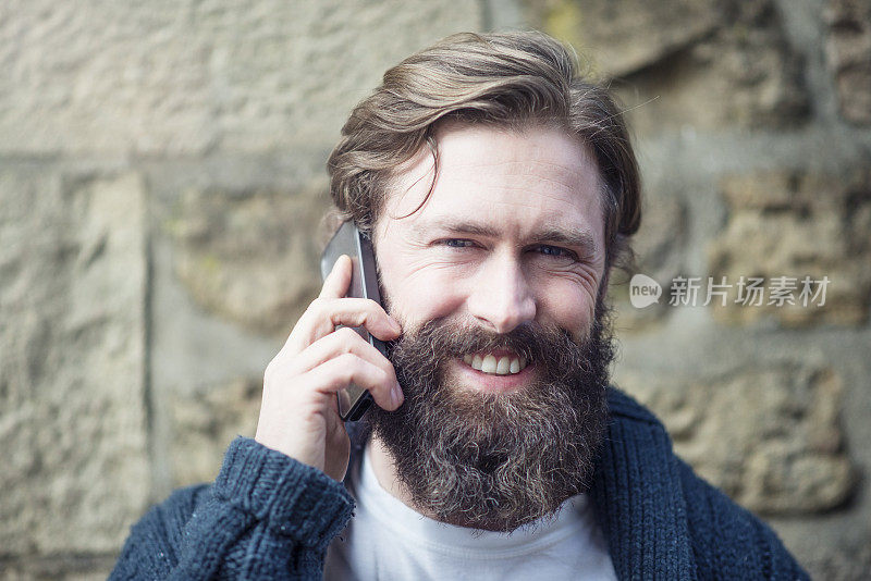 微笑的大胡子男人拿着手机