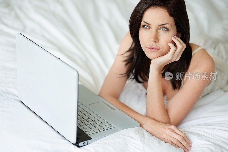 体贴的白种女人躺在床上拿着笔记本电脑