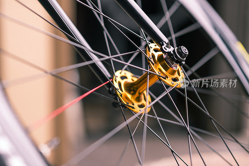 自行车轮子上的金色轮毂和红色辐条。