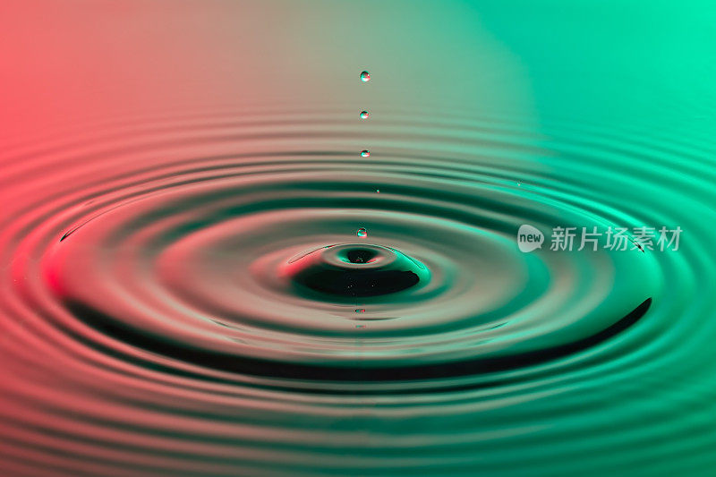 水滴近距离与同心涟漪在五颜六色的红色和绿色表面