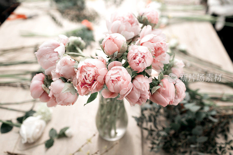 粉红色的牡丹花瓶在木地板和散景背景-复古风格的照片。软的焦点。