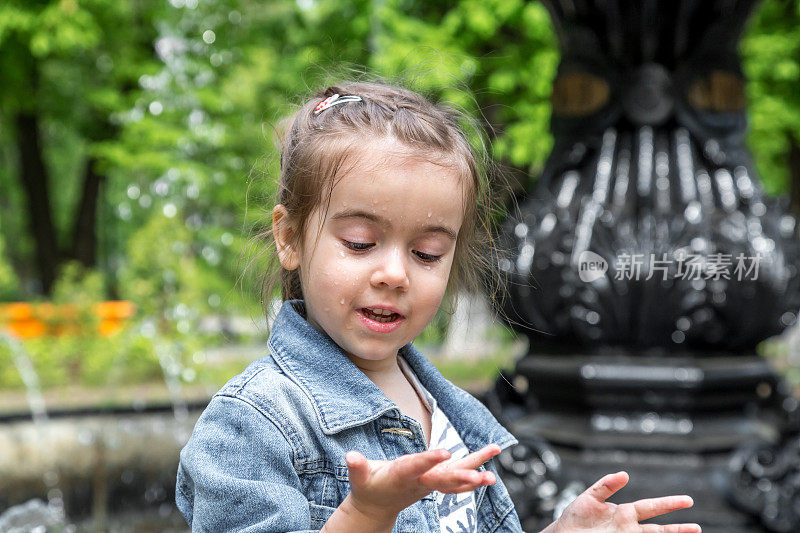 可爱的小女孩在喷泉里把手弄湿了
