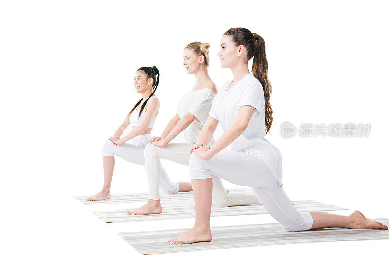 微笑的年轻妇女在运动服装练习瑜伽在垫子上孤立的白色