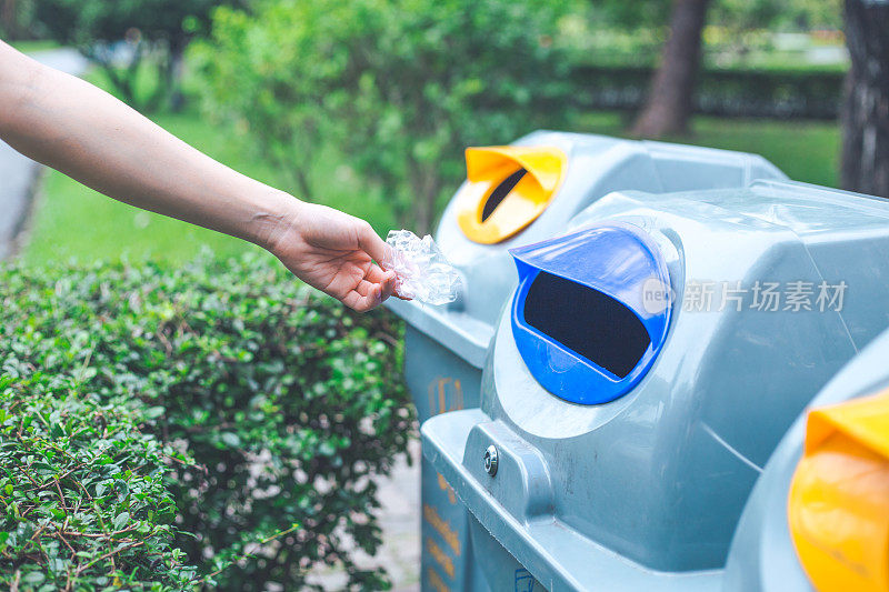 用手把塑料袋扔进垃圾桶。环境保护和全球变暖的概念。