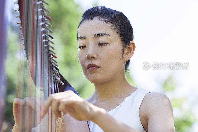 在户外弹奏竖琴的女人