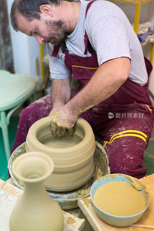 年轻的陶工在陶轮上做花瓶