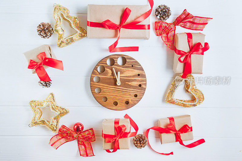顶视图圣诞假期的组成与礼物在牛皮纸与红色缎带，装饰，手表和笔记本在白色木质背景与复制空间为您的文本。有选择性的重点