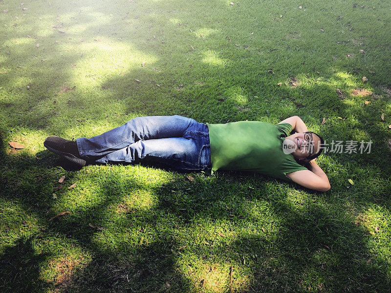 日本人在夏日的阳光下躺在绿色的草地上休息。