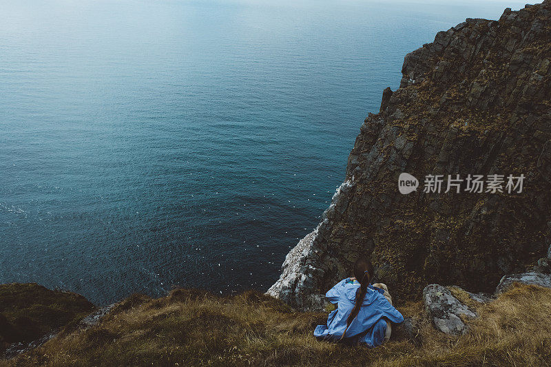 在挪威徒步旅行和看海后带着狗休息的女人