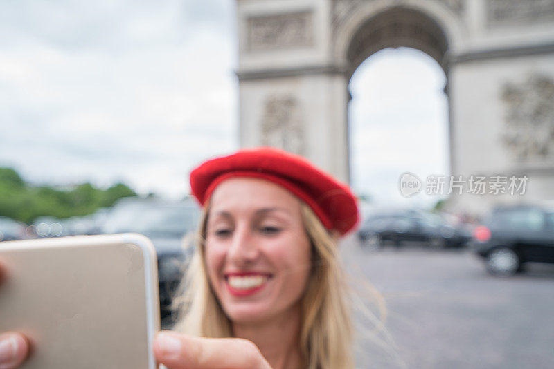 年轻女子在巴黎用手机自拍，人们在巴黎旅游的城市首都概念