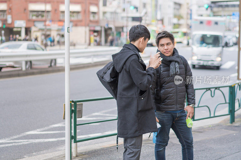 年轻的日本男子和亚洲朋友寻找旅游地点使用手机和花时间在日本一起